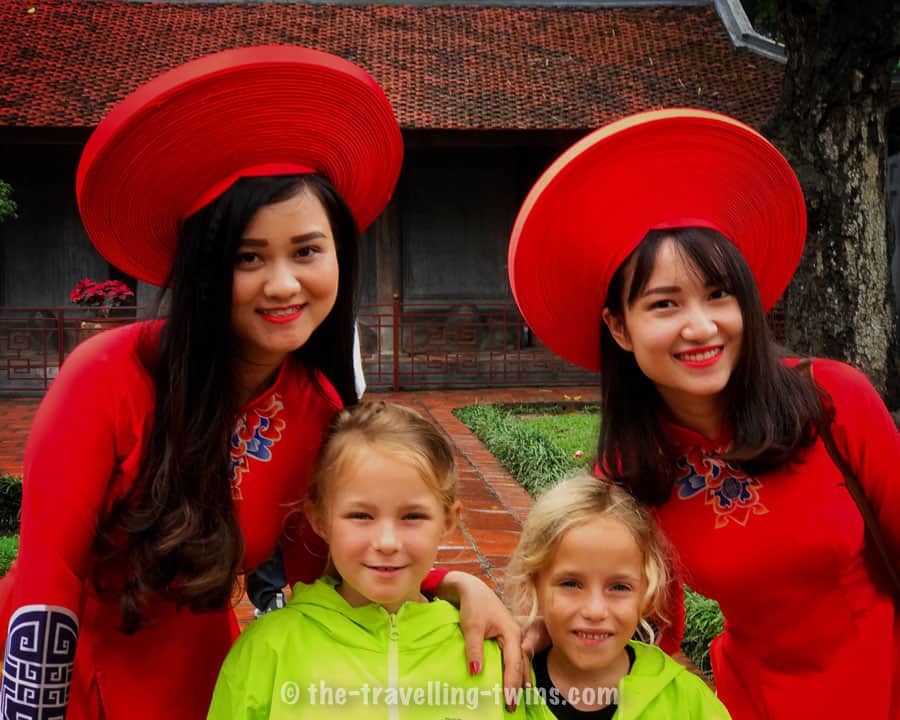 our girls with two vietnamese women dressed in traditional Ao Dai- long fitted dress. they were as well wearing wooden clogs - guoc moc vietnam souvenirs
