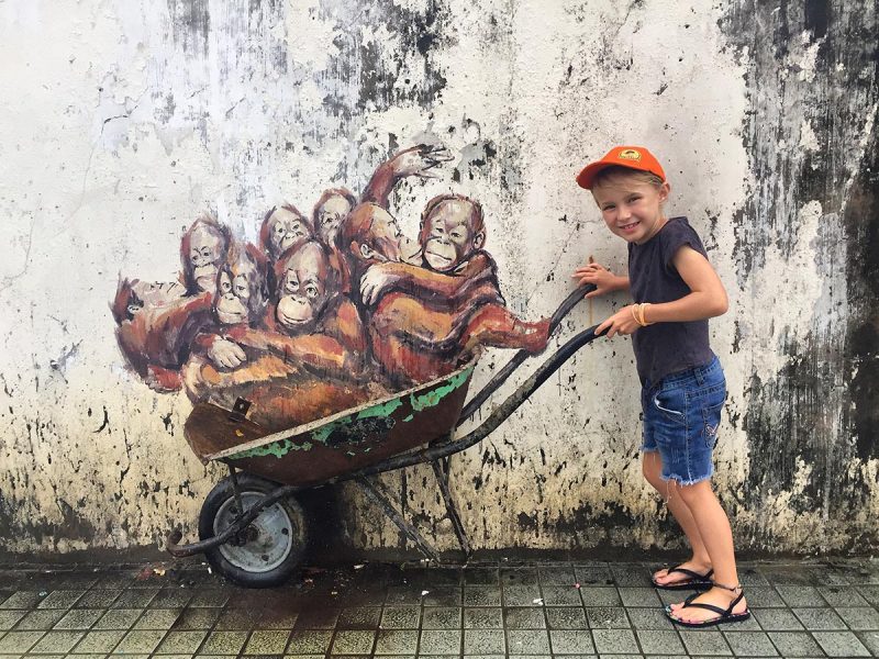 girl standing at the mural with orangutans in Kuching, things to do in kuching with kids